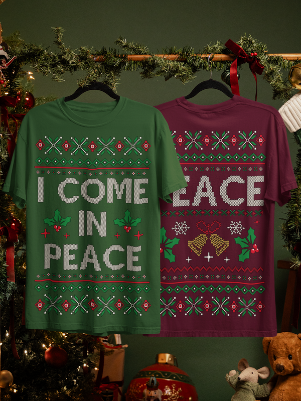 Two Christmas-themed t-shirts on hangers with festive decorations in the background.